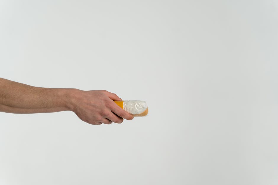 A hand holds a transparent bag containing a white substance against a neutral backdrop.