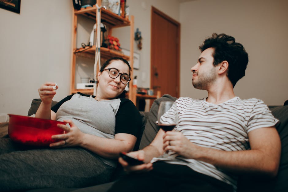 A couple enjoys a cozy evening at home with snacks and wine, captured in a relaxed indoor setting.