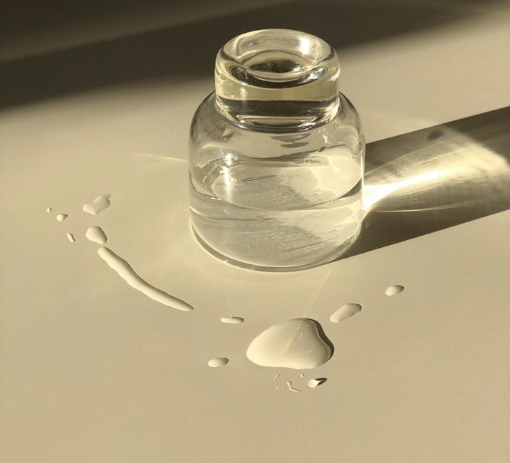 Minimalist glass bottle with water droplets captured in soft lighting on a white surface.