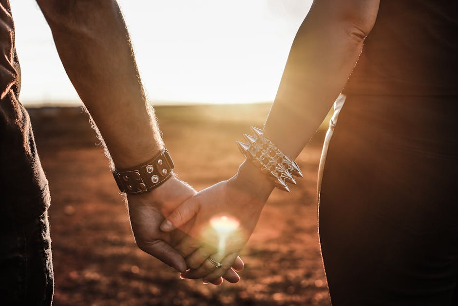 Close-up of a couple holding hands at sunset with stylish bracelets. Perfect for themes of love and connection.
