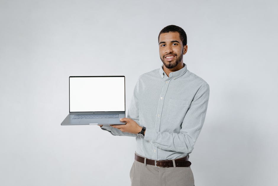 African American man with facial hair holding a laptop with a blank screen, perfect for technology mockups.