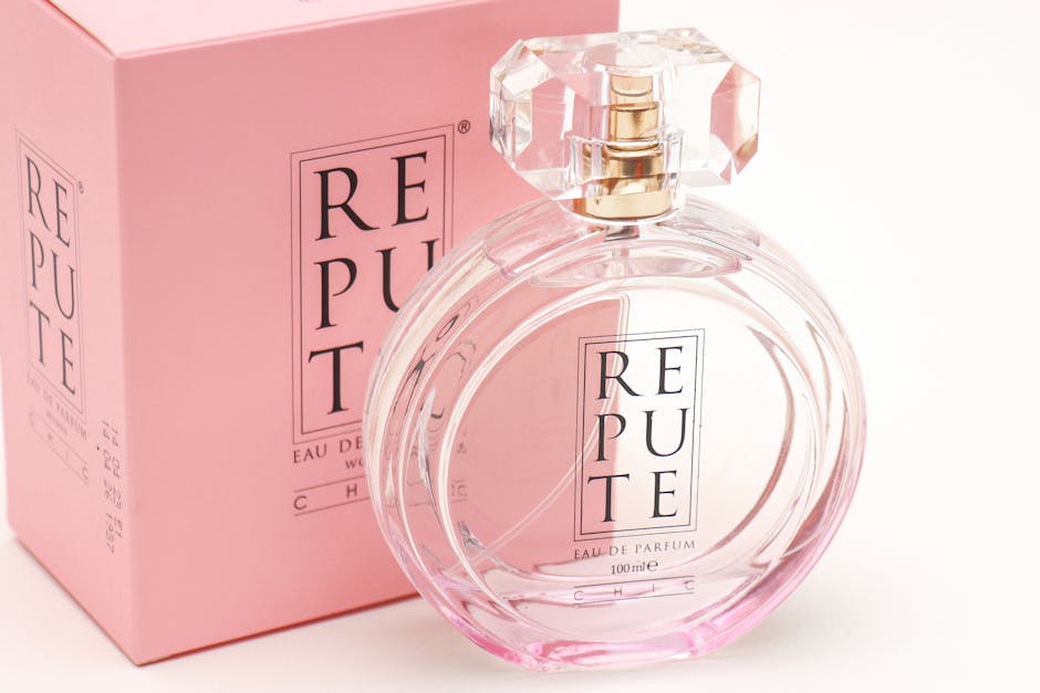 Elegant glass perfume bottle labeled 'Repute' beside its stylish pink packaging, showcasing luxury design.