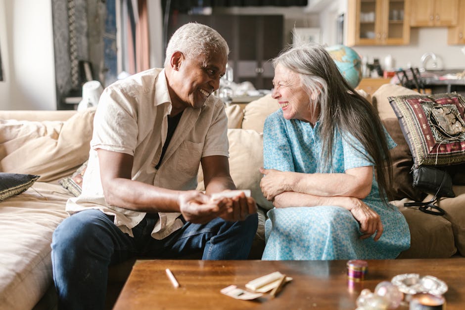 Happy elderly couple sharing a joyful moment on the couch indoors. Warm and bright atmosphere.