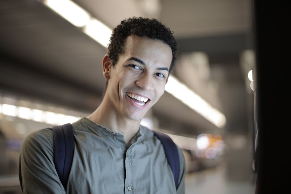 Portrait of a happy young man with curly hair and a backpack in a modern indoor setting.