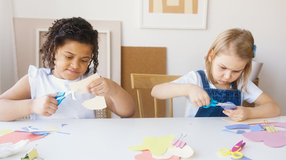Two young girls focusing on a colorful paper crafting activity indoors.