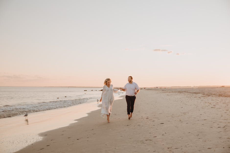 A couple holding hands and walking on a serene beach during sunset, capturing a romantic moment.