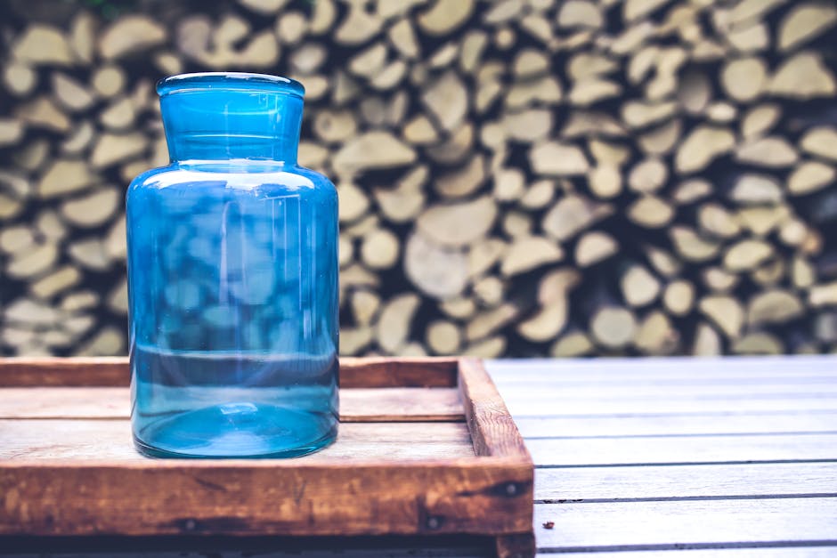 A vintage turquoise glass jar displayed on a wooden tray with a blurred wooden background.