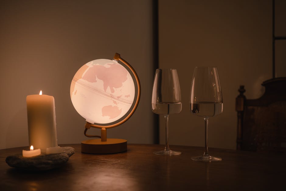 Warm indoor ambiance with a glowing globe, candlelight, and wine glasses on a wooden table.