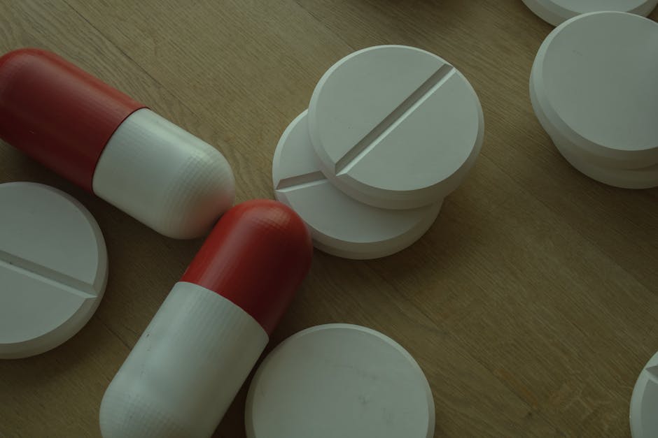 Assorted white tablets and red capsules on a wooden surface, emphasizing medications.